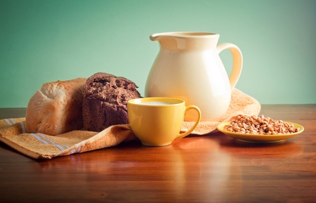 Pitcher of milk, bread, and wheat on wooden tableの写真素材