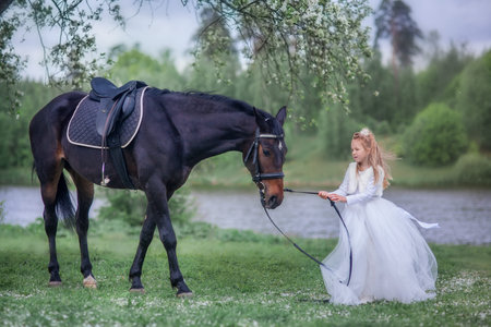 Girl with black horse in blossom gardenの写真素材
