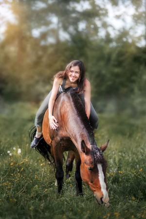 Young woman  with her horse walking on summer fieldの写真素材