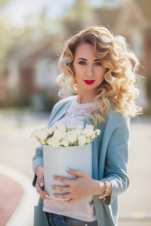 Beautiful woman with paper box of flowers outdoor portrait on town  streetの写真素材