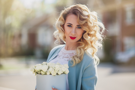 Beautiful woman with paper box of flowers outdoor portrait on town  streetの写真素材