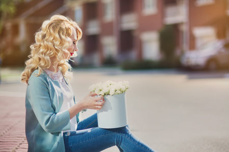 Beautiful woman with paper box of flowers outdoor portrait on town  street