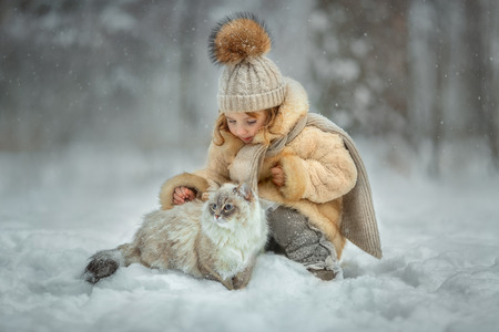 Little girl portrait with cat in winter parkの写真素材