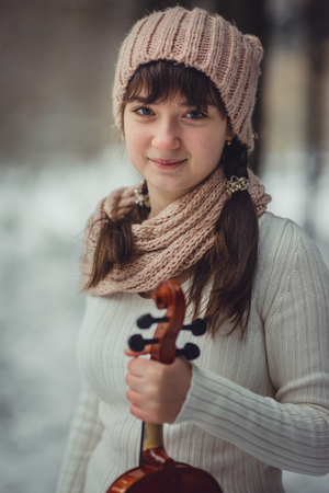 Teenage girl portrait with violin in winter parkの写真素材