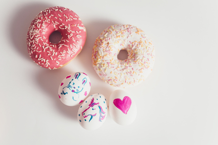 Easter eggs with donuts on the white table in daylightの写真素材