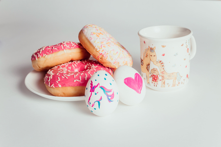 Easter eggs with donuts on the white table in daylightの写真素材