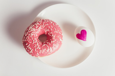 Easter eggs with donuts on the white table in daylightの写真素材