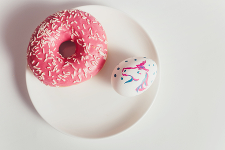 Easter eggs with donuts on the white table in daylightの写真素材