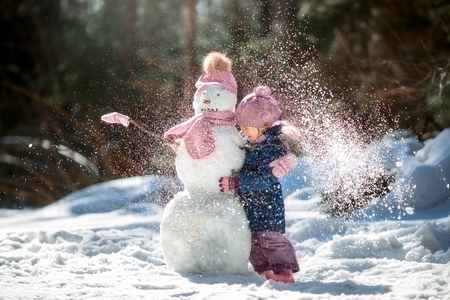 Little girl with snowman in winter parkの写真素材