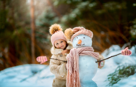 Little girl with snowman in winter parkの写真素材
