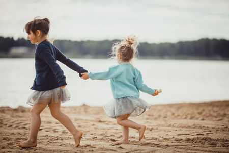 Two sisters playing on the shore of the lake at summer eveningの写真素材
