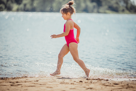Little girl have fun on the coast of the lakeの写真素材
