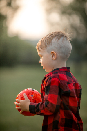 A little boy with a football with his dog in the parkの写真素材