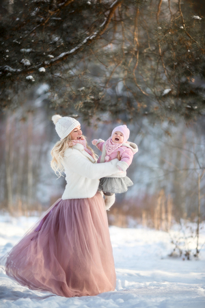 Mother and daughter winter portrait in snowy sunny parkの写真素材