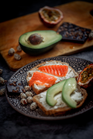 Launch with Dietary sandwiches with grain bread, cream cheese and avocado, red fish and passion fruit with dark chocolate on desertの写真素材
