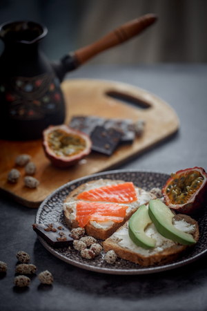 Launch with Dietary sandwiches with grain bread, cream cheese and avocado, red fish and passion fruit with dark chocolate on desertの写真素材