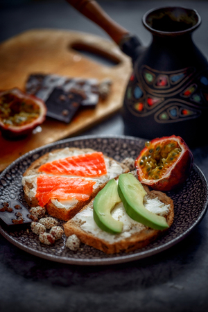 Launch with Dietary sandwiches with grain bread, cream cheese and avocado, red fish and passion fruit with dark chocolate on desertの写真素材