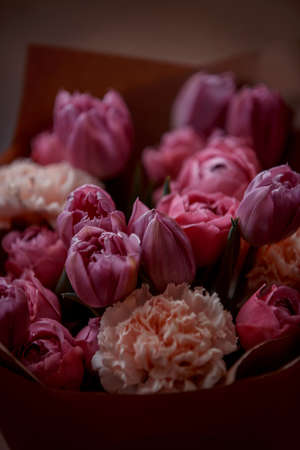 Bouquet of beautiful flowers with purple peony roses, carnations and tulips, in the craft paperの写真素材