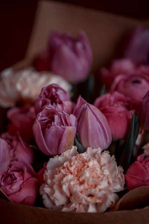 Bouquet of beautiful flowers with purple peony roses, carnations and tulips, in the craft paperの写真素材