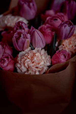 Bouquet of beautiful flowers with purple peony roses, carnations and tulips, in the craft paperの写真素材