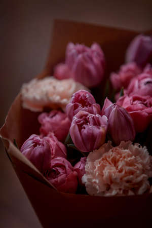 Bouquet of beautiful flowers with purple peony roses, carnations and tulips, in the craft paperの写真素材