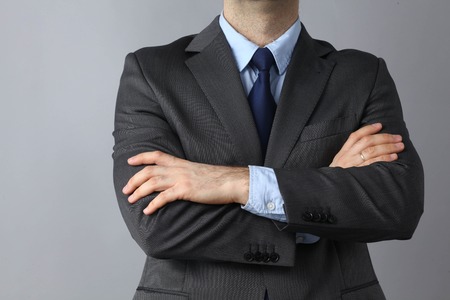 Businessman standing with arms crossed isolated on grey backgroundの写真素材