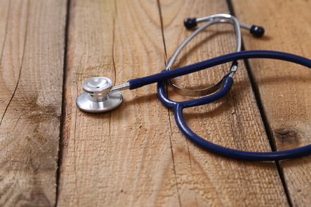 Closeup of a medical stethoscope, isolated on wooden background.の写真素材