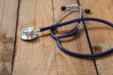Closeup of a medical stethoscope, isolated on wooden background.の写真素材