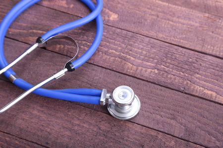 Closeup of a medical stethoscope, isolated on wooden background.の写真素材