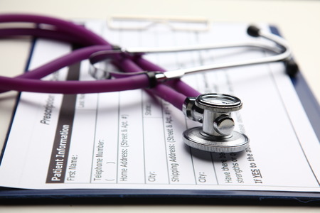Stethoscope with cardiogram lying on desk in hospital.の写真素材