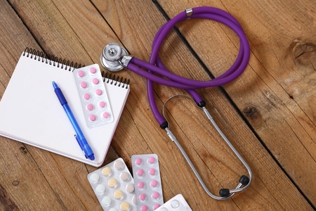 Stethoscope and tablets isolated on wooden background.の写真素材