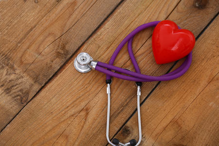 A heart with a stethoscope, isolated on wooden backgroundの写真素材