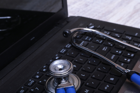 A blue stethoscope on a dark laptop computerの写真素材