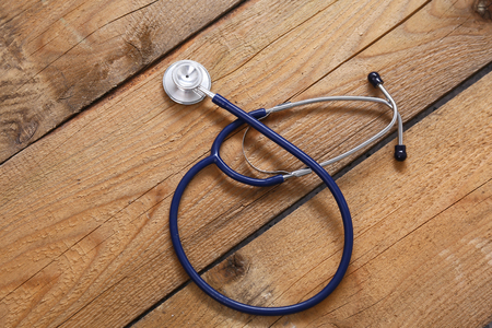 Closeup of a medical stethoscope, isolated on wooden background.の写真素材