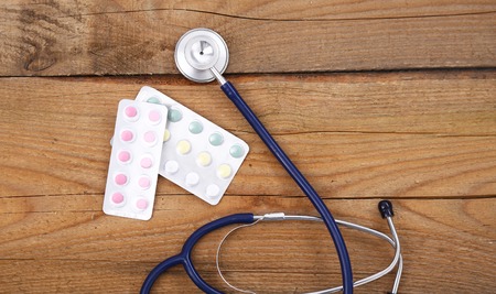 Stethoscope and tablets isolated on wooden background.の写真素材