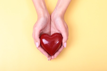 Female hands giving red heart, isolated on gold background.の写真素材