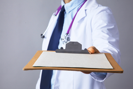 The doctor in a white coat with a stethoscope holding a folder .の写真素材