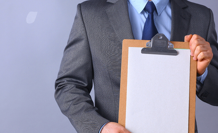 Young man standing with folder, isolated on gray background .の写真素材