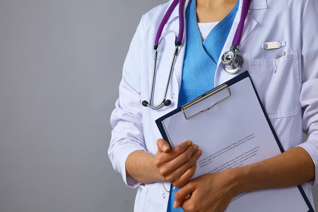 The woman doctor in a white coat with a stethoscope holding a folderの写真素材