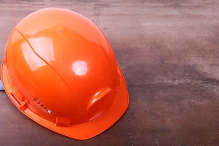Orange safety engineer helmet on brown backgroundの写真素材