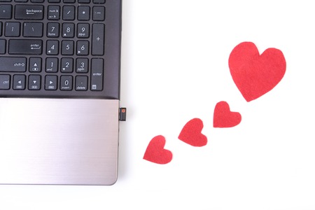 Red heart with laptop on wooden tableの写真素材