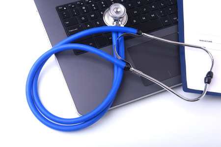 A medical stethoscope near a laptop on a wooden table, on whiteの写真素材