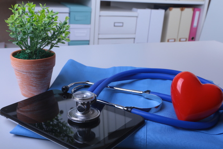 Doctor coat with medical stethoscope and red heart on the deskの写真素材