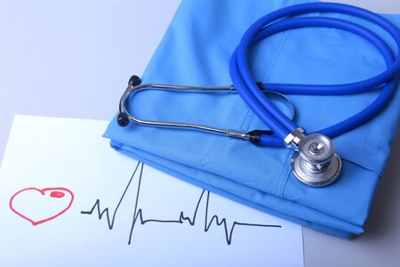 Cardiogram with medical stethoscope and doctor coat on tableの写真素材