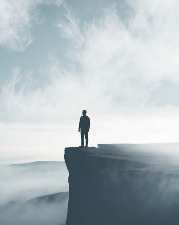AI Generated. silhouette of a person standing on a cliff overlooking a misty landscapeの素材
