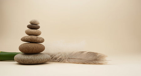 This serene image captures a zen still life with carefully stacked stones, a delicate feather, and a vibrant green bamboo stalk. It evokes peace and balance.の素材