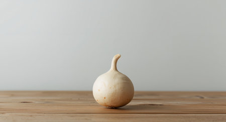 Closeup of a single white onion placed on a rustic wooden table. The smooth, lightcolored onion contrasts with the warm tones of the wood, creating a minimalist and natural feel.の素材