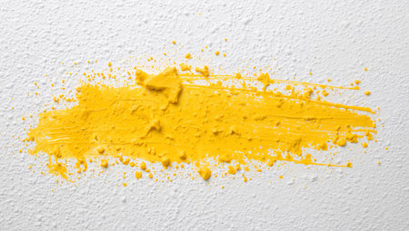A vivid yellow streak dominates the textured white background, exhibiting a blend of rough and smooth textures. The light illuminates the surface unevenly.の素材