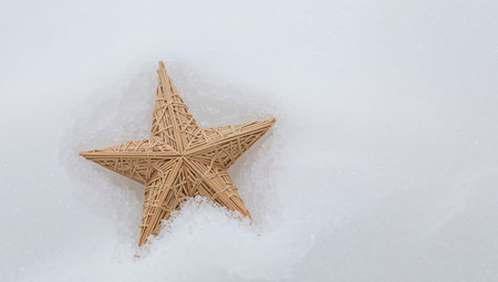 A fivepointed, wicker star is placed on a textured white surface. The lighting is soft and diffused, highlighting the patterns of the woven material.の素材