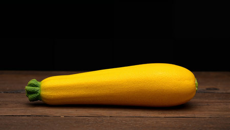 A yellow oblong form sits on a dark brown wooden surface. The lighting accentuates the textured skin, creating a visual contrast.の素材